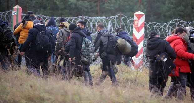 Migrants walk along the barbed wire fence at the Belarus-Poland border. About 15,000 Polish troops have joined riot police and guards at the border. Photograph: Leonid Shcheglov/BelTA pool photo via AP