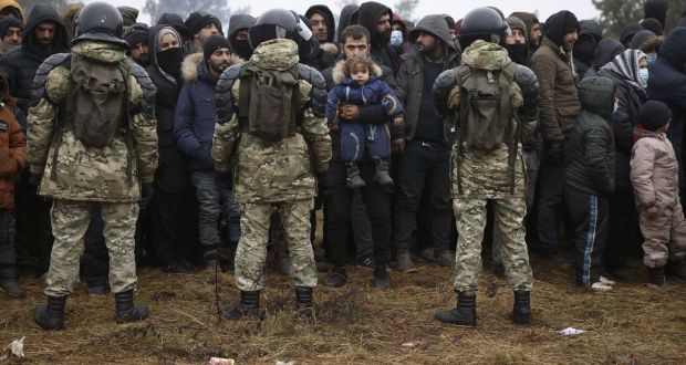 Migrants stand in front of Belarusian servicemen as they gather in a camp near the Belarusian-Polish border in the Grodno region. Photograph: Oksana Manchuk/Belta/AFP via Getty