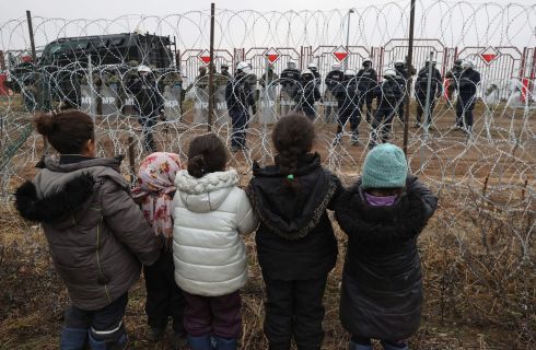 BORDER CRISIS: Children looking at Polish police and military police through barbed wire at the Belarusian-Polish border near the Bruzgi-Kuznica checkpoint, in the Grodno region of Belarus. Asylum-seekers, refugees and migrants from the Middle East arrived at the Belarusian-Polish checkpoint aiming to cross the border. Thousands of people, who want to obtain asylum in the European Union, have been trapped in low temperatures at the border since November 8th.  Photograph: Maxim Guchek/Belta handout/EPA