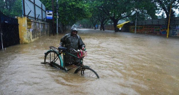 A man pushes his cycle past a flooded street in Chennai, in the southern Indian state of Tamil Nadu. Photograph: R. Parthibhan/AP Photo