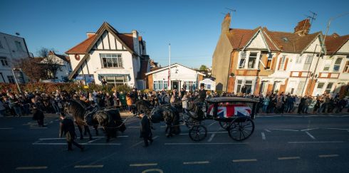 Mourners pay their respects as the horse-drawn hearse carrying the coffin of David Amess pauses outside his constituency office at Iveagh Hall, Leigh-on-Sea, following his funeral service. Photograph: Aaron Chown/PA 
