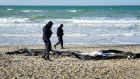 French police officers examine a deflated dinghy on the beach in Wimereux near Calais on Thursday. Photograph:  Gareth Fuller/PA Wire