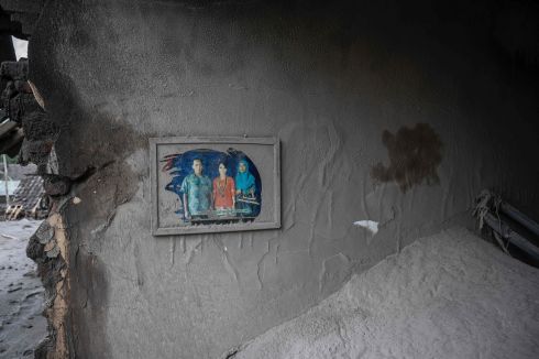 ASHES AND DUST: A family portrait hangs on the wall in a damaged house at Sumber Wuluh village, Lumajang, Indonesia, following a volcanic eruption from Mount Semeru known to have killed a least 14 people. Photograph: Juni Kriswanto/AFP/Getty
