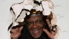 Desmond Tutu peering through a hole he knocked in a wall at St. Luke's Hospital for the Clergy, in central London. Desmond Tutu, the Nobel Peace Prize-winning activist for racial justice and LGBT rights, has died aged 90. He had been treated in hospital several times since 2015, after being diagnosed with prostate cancer in 1997. Photograph Rebecca Reid/PA Wire
