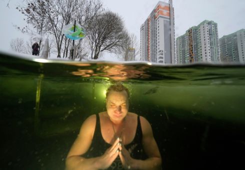 EXTREME EXERCISE: A woman bathes near a hole in ice sitting on top of a pond in St Petersburg, Russia, where the temperature is -7C (19F). Photograph: Dmitri Lovetsky/AP Photo
