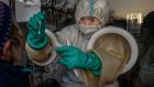 A medical worker reaches through protective gloves as she administers a nucleic acid test at a private outdoor clinic on December 27th in Beijing. Photograph: Kevin Frayer/Getty Images