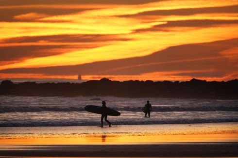 SUN AND SURF: Surfers enter the sea as the sun rises over Tynemouth on the northeast coast of England. Photograph: Owen Humphreys/PA Wire
