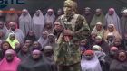 An alleged Boko Haram soldier standing in front of a group of girls alleged to be some of the 276 abducted Chibok schoolgirls held since April 2014, in an unknown location. Photograph: Militant video/Site Institute via AP