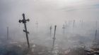 CROSSES TO THE FALLEN: Crosses emerge from smoke in a rubbish-strewn cemetery in Mykolaiv, southern Ukraine, as the Russian invasion of the country nears a month so far in duration. Photograph: Bulent Kilic/AFP/Getty 
