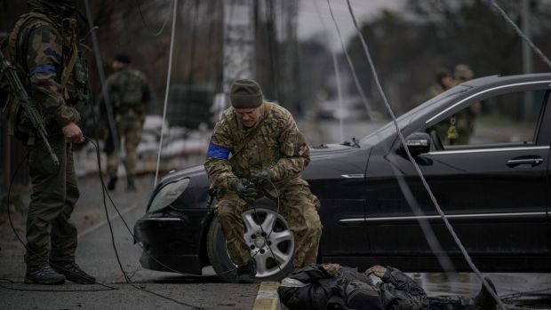 A Ukrainian serviceman grimaces after dragging the dead body of a civilian with a cable to check for booby traps, in the formerly Russian-occupied Kyiv suburb of Bucha, Ukraine on Saturday. Photograph: Vadim Ghirda/AP