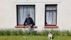 Andy Quinn and his dog Oxo enjoy the sunshine outside their home on the main street of Castletown, Co Laois. Photograph: Alan Betson