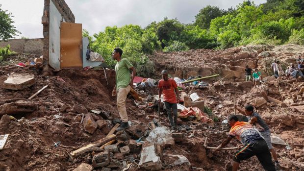 Family members assist with clearing debris during efforts to locate 10 people unaccounted for from a township outside Durban. Photograph: Phill Magakoe/AFP via Getty