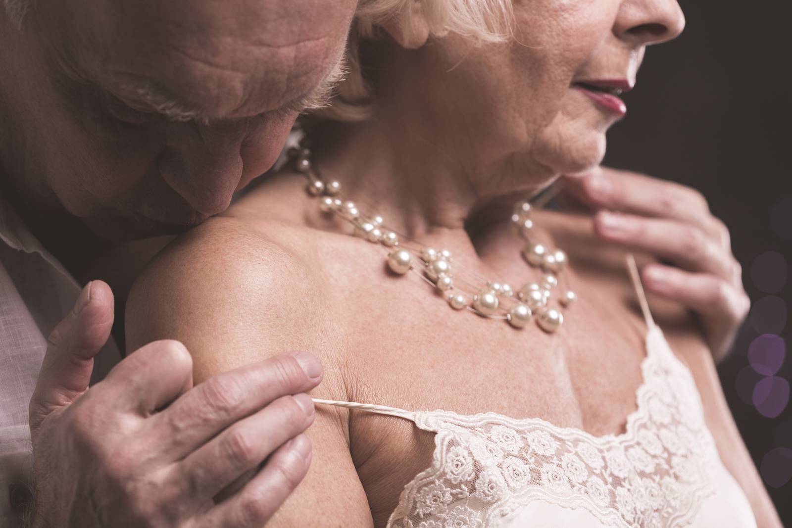 Senior man kissing female arm old age sex