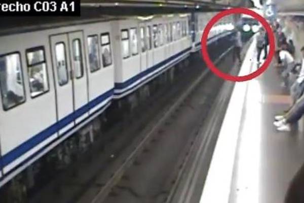 Woman distracted by mobile phone falls in front of oncoming train
