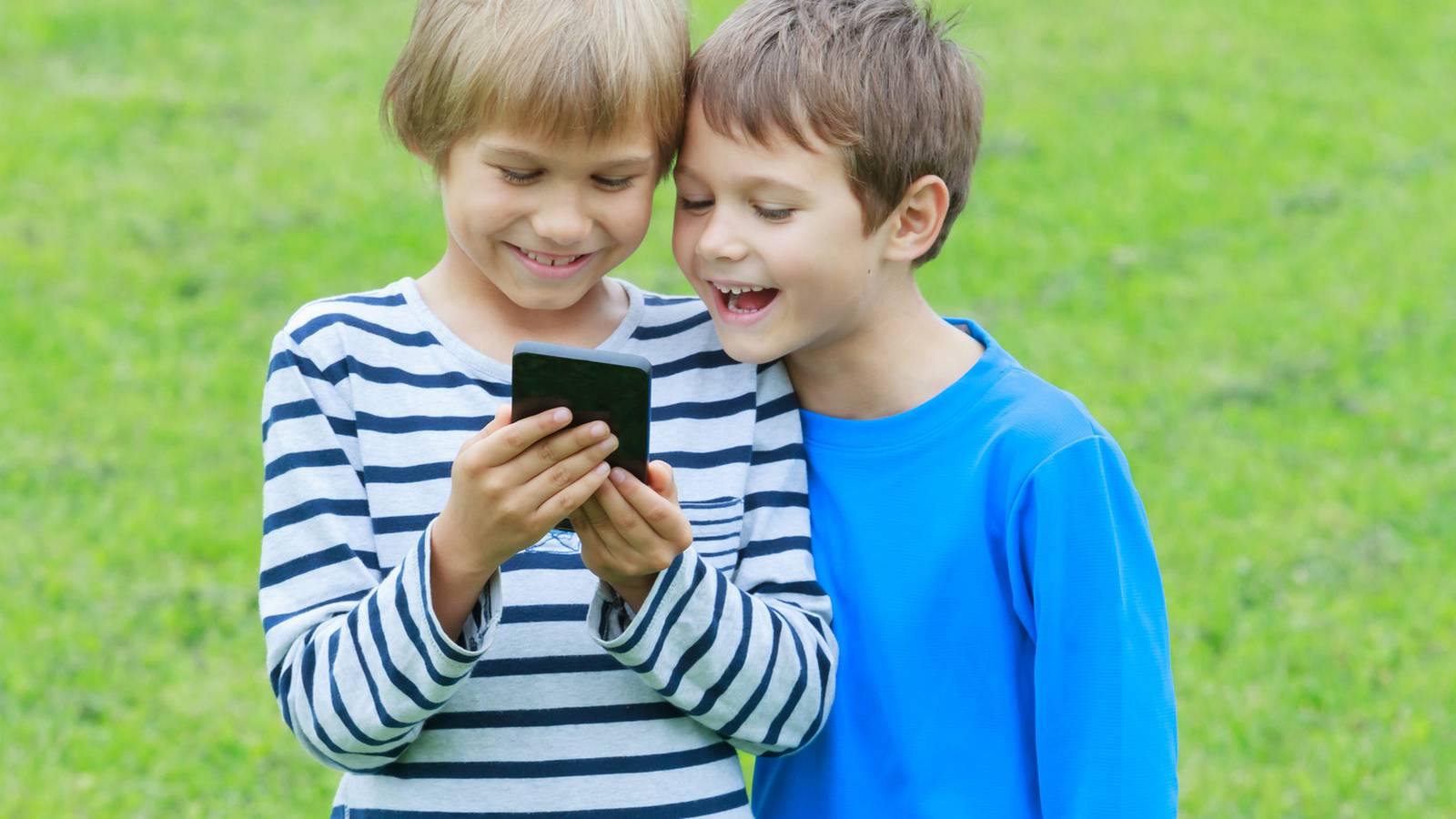18 где мальчик с мальчиком. Ребенок со смартфоном. Мальчик с телефоном. Дети на траве со смартфонами. Ребёнок в иелефоне вертикальная.