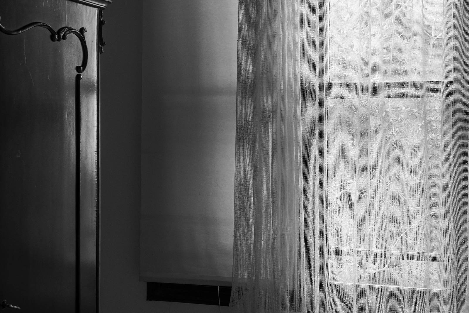 Wooden window frame with transparent hand-made curtains with a part of an old wardrobe in an old house. Photograph: iStock