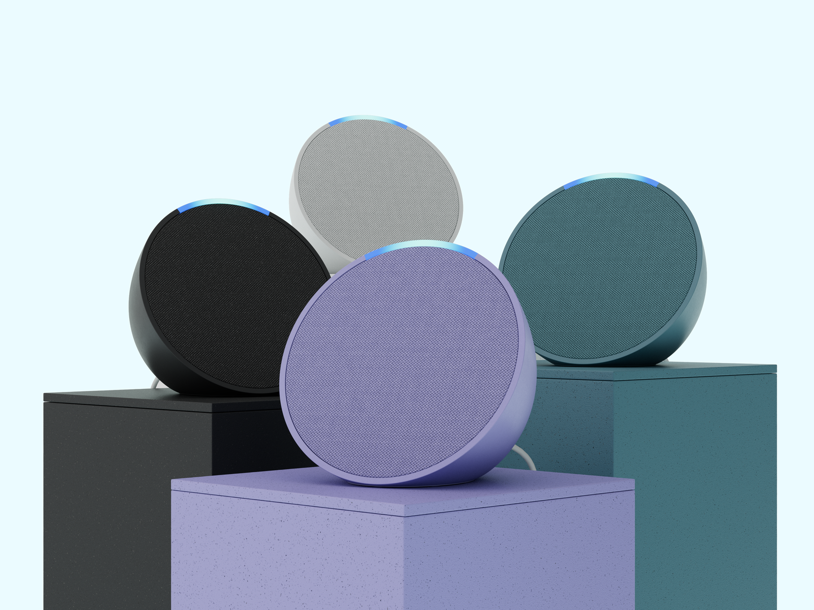 Group shot of four round Amazon Echo Pop speakers, each sitting on a colour matched pedestal