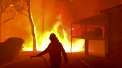 Australian firefighters reach badly burnt towns as weather cools