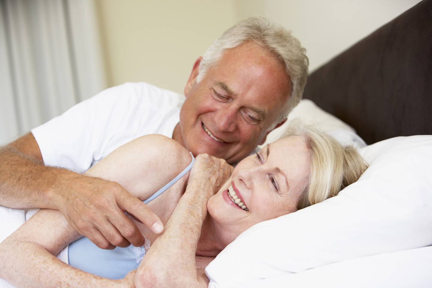 Senior Couple Relaxing On Bed Laughing Together older old sex