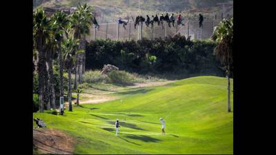 Golfers play on as migrants scale obstacle to life in Europe