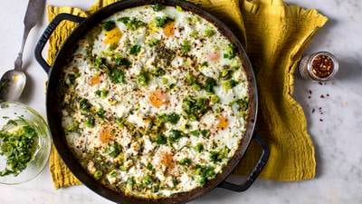 An oven to table dish of baked polenta with eggs, greens and cheese