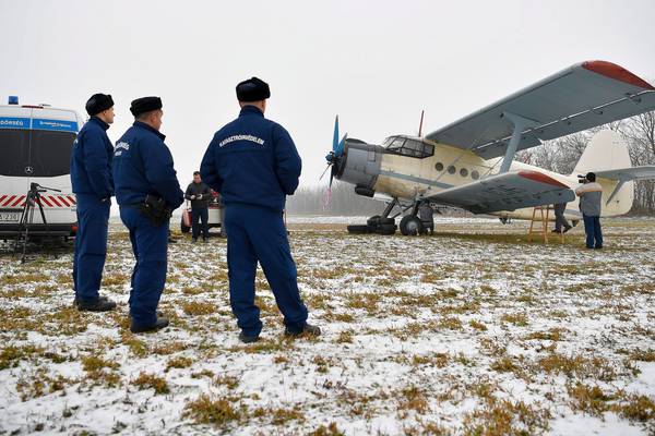Police chase pilot after vintage biplane lands in Hungarian field with migrants