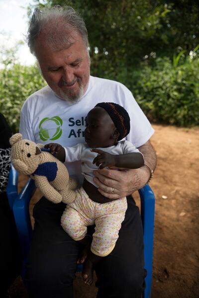 Ronan Scully with baby Joseph in Kiyumo in Eastern Uganda with a present of a teddy bear called Philly, one of many gifts from children from schools in Ireland.