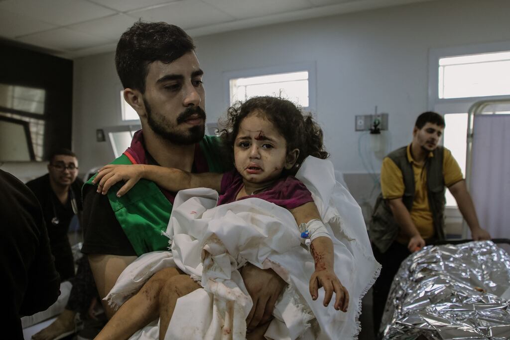 A young man cradles an injured girl in a Gaza hospital. Israeli air strikes have killed thousands of children in Gaza. Photograph: Youssef Alzanoun/Middle East Images/AFP via Getty Images