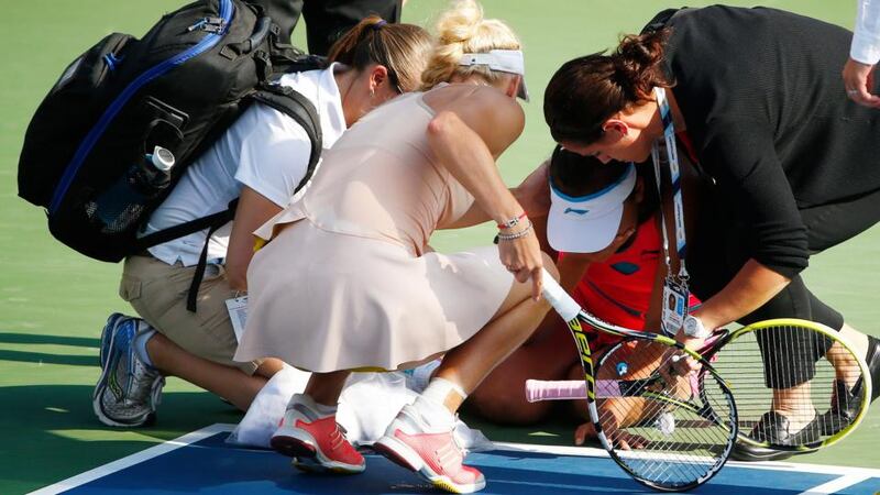 Caroline Wozniacki of Denmark (second left) checks on Shuai Peng of China  after  she slumped to the ground  during their semi finals at the  US Open. Photograph: Andrew Gombart/ EPA