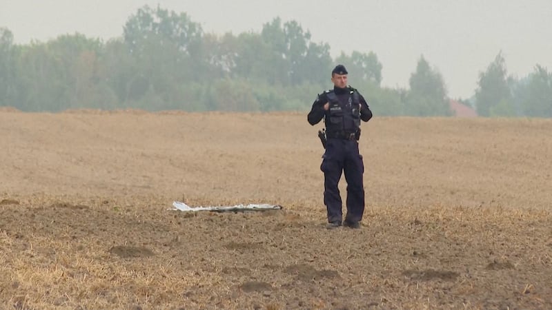 A Polish police officer stands near a unmanned aerial vehicle fragment last October after Russian drones violated Polish airspace in Czesniki, Lublin