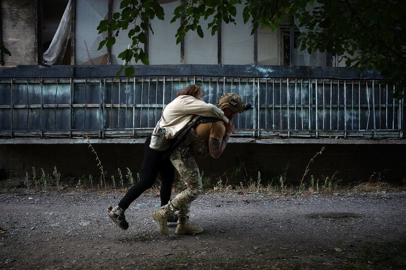A member of a police team called the White Angels helps a resident evacuate in Kostiantynivka, Ukraine.  Photograph: Tyler Hicks/The New York Times
                      