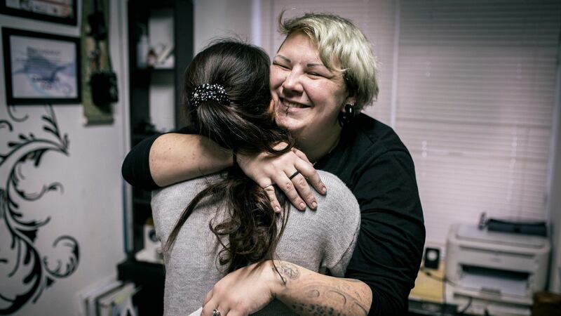 Yevgeniya Zakhar hugs a woman she gave a tattoo to conceal a scar from a domestic violence attack. Photograph: Vadim Braydov/AP