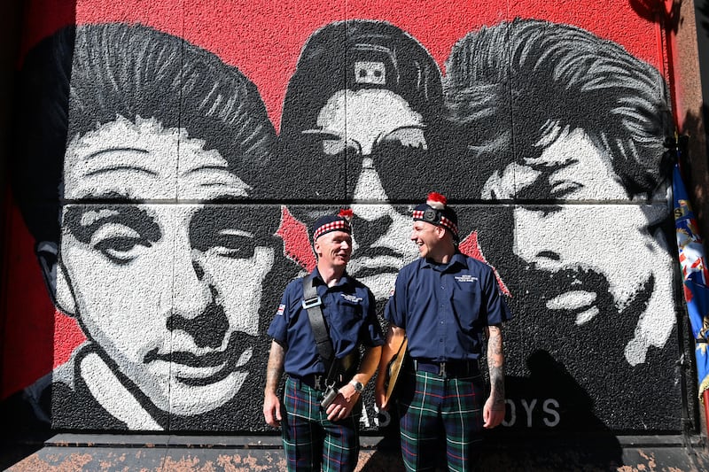 Members of a flute band chat in front of a mural of the band The Beastie Boys as they prepare to take part in a Twelfth of July parade in Belfast. Photograph: Charles McQuillan/Getty