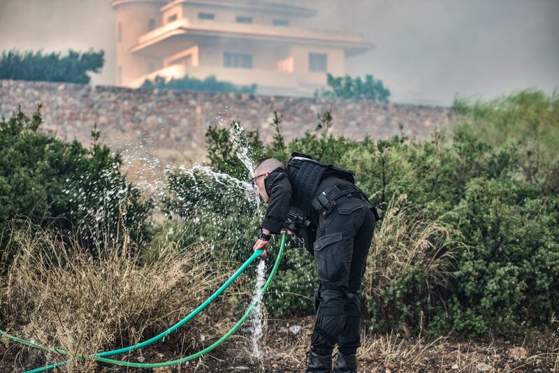 A police officer washes his face to cool down as a fire rages in the Lagonisi area, 35km from Athens, on Monday. Photograph: Spyros Bakalis/AFP via Getty