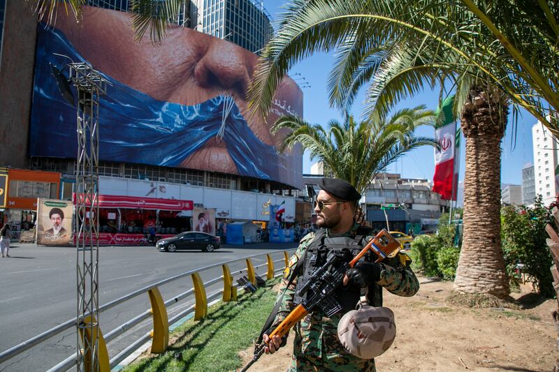 An Iranian police officer stands before a poster depicting the mouth of US president Donald Trump, gagged by a blue ribbon in the shape of the Strait of Hormuz, in Tehran, on Saturday. Photograph: Majid Saeedi/Getty
