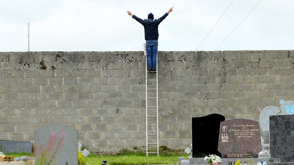 A fan watches the Roscommon SFC semi-final between St Brigid’s and Boyle at Dr Hyde Park from the adjoining St Coman’s cemetery. Photograph: James Crombie/Inpho
