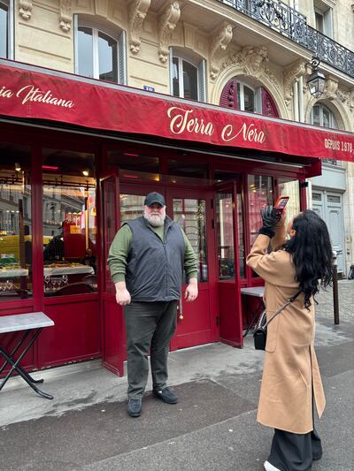 Valerio Abate, owner of a restaurant made famous by its appearance in the series Emily in Paris, stands outside as a tourist takes a photograph. Photograph: Naomi O'Leary