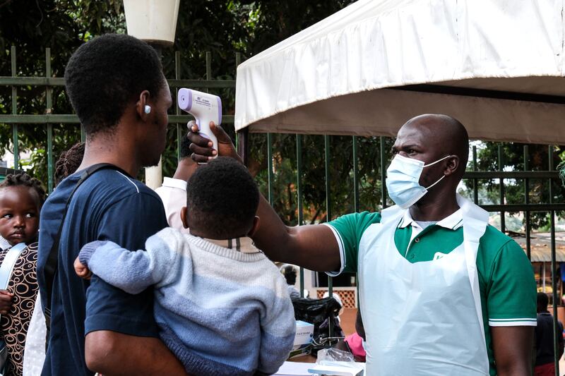 A health official uses a thermometer to screen people in front of Kibuli Muslim Hospital in Kampala, Uganda. Photograph: Hajarah Nalwadda/AP