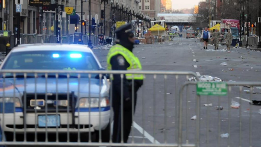 A police officer guards the corner of Boylston and Arlington Streets at dawn today with the Boston Marathon finish line bridge in the background. Security is especially tight in the city after two explosions yesterday killed three people and injured at least 141. Photograph: Darren McCollester/Getty Images