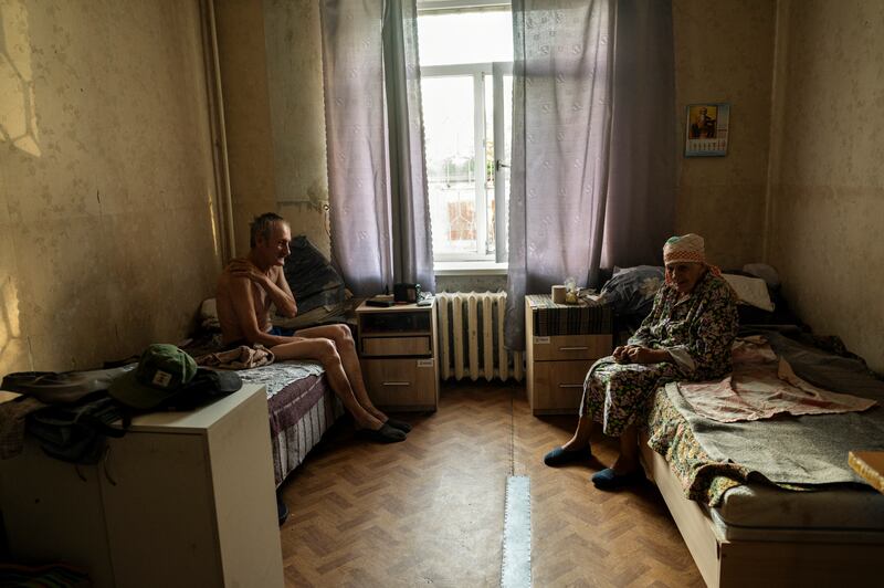 Liudmyla Mizernyi (87), sits beside her son, Viktor Mizernyi (58), who was left disabled when a round landed on the house where they were sheltering, in Zaporizhzhia. Photograph: Lynsey Addario/New York Times
                      