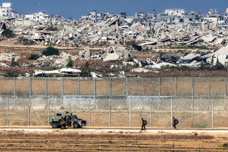 Israeli army soldiers walk towards an armoured vehicle at a position along the border fence with the Gaza Strip in southern Israel on September 30, 2025. The US president on September 29 laid out a plan to end the war in Gaza and Israeli Prime Minister Benjamin Netanyahu said he backed the proposal. The two allies demanded approval by Hamas, whose October 7, 2023 attack triggered a massive Israeli offensive, with Netanyahu warning he will "finish the job" if Hamas says no. (Photo by Jack GUEZ / AFP) (Photo by JACK GUEZ/AFP via Getty Images)