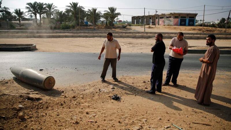 Palestinians look at an unexploded Israeli shell that landed on the main road outside the town of Deir Al-Balah in  central Gaza . Photograph: Finbarr O’Reilly/Reuters