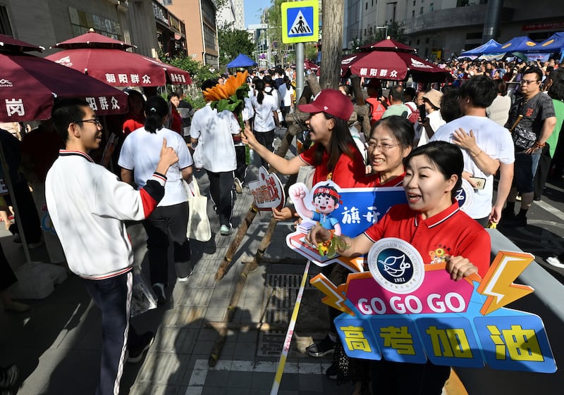 School staff members welcome students as they enter a school during China's National College Entrance Examination, known as "gaokao", outside a high school in Beijing. Photo: Adek Berry/AFP