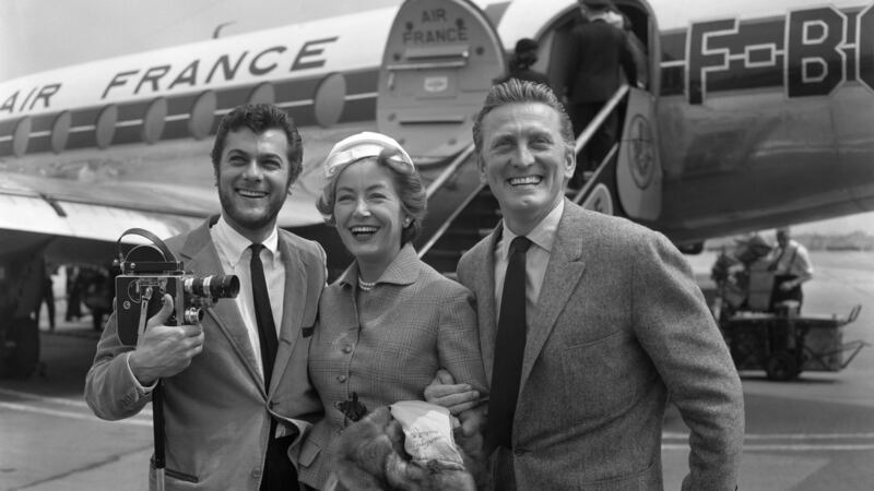 A 1957 file photograph of  Kirk Douglas and his wife Anne Buydens being met by Tony Curtis, left, on their arrival at London Airport from Paris. Photograph: PA Wire.