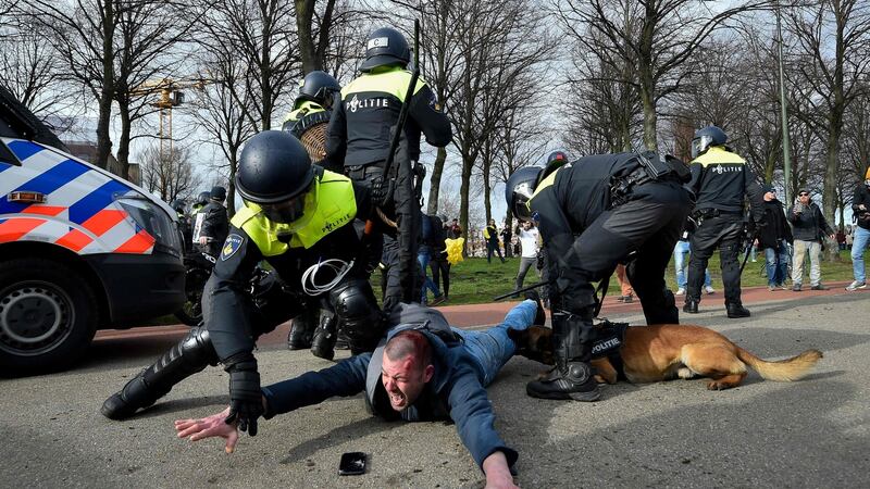 Dutch anti-riot police officers restrain a protester during a demonstration at Malieveld in The Hague. Photograph: Getty