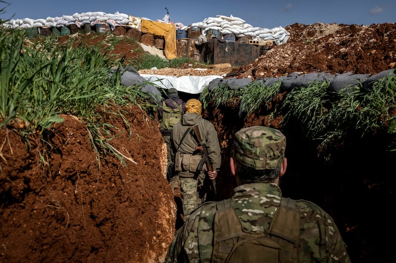 Fighters for the militant group Hayat Tahrir al-Sham make their way through a trench on the front lines near the town of Maaret al-Nasaan, Idlib Province, Syria. Photograph: Ivor Prickett/New York Times
                      