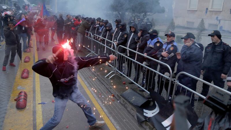 An Albanian opposition supporter throws a firework during an anti-government protest in Tirana. Photograph: Malton Dibra/EPA
