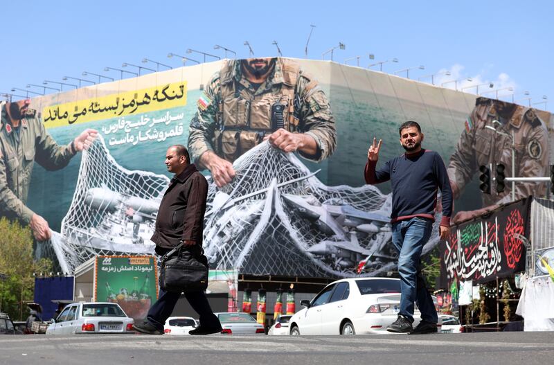 Iranians pass a huge political billboard reading in Persian 'The Strait of Hormuz will remain closed', in Enghelb square in Tehran, Iran, on Sunday