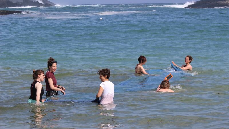 Artists washing sea cyanotype from the Tombolo 19 residency and exhibition at Brow Head. Photograph Fellipe Lopes