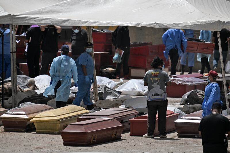 Forensic experts stand amid victims and coffins in La Guaira,Venezuela. Photograph: Juan BARRETO / AFP via Getty Images